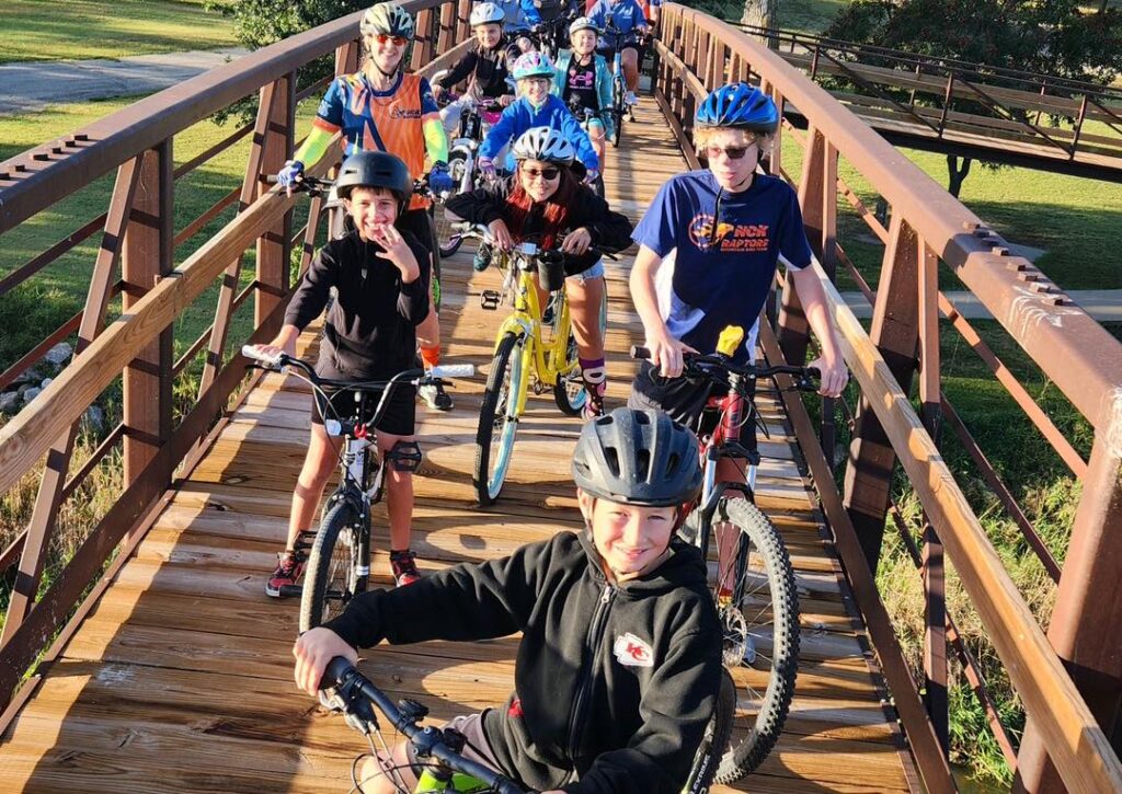 A group of kids riding their bike on a bridge.