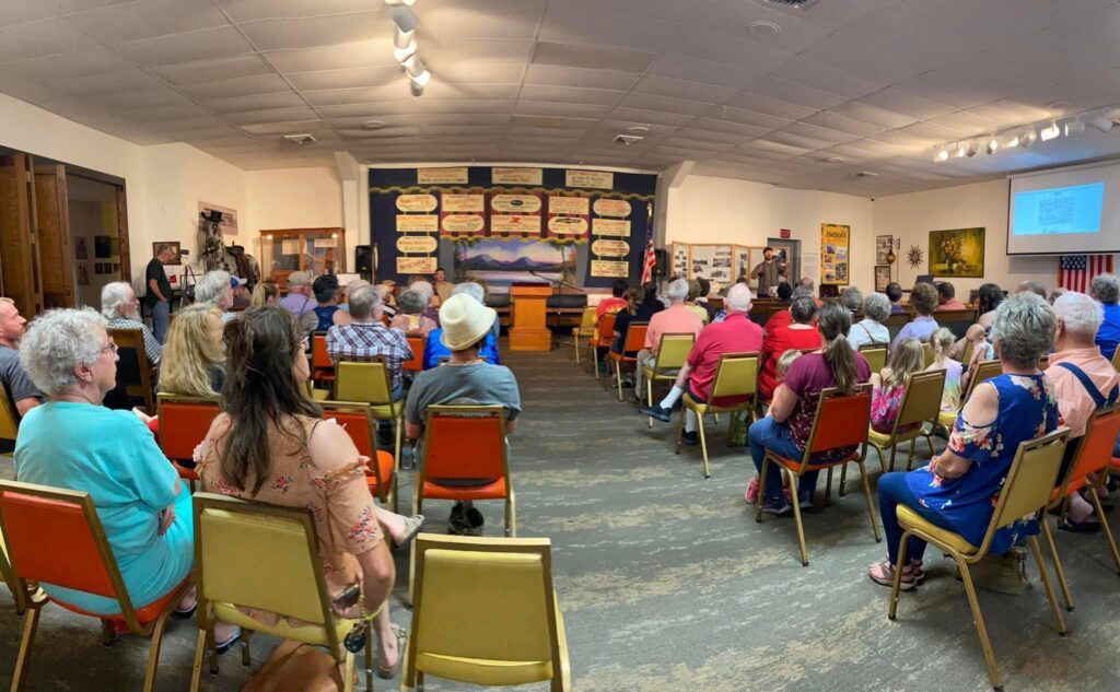 Large meeting with many people sitting and listening to a program.