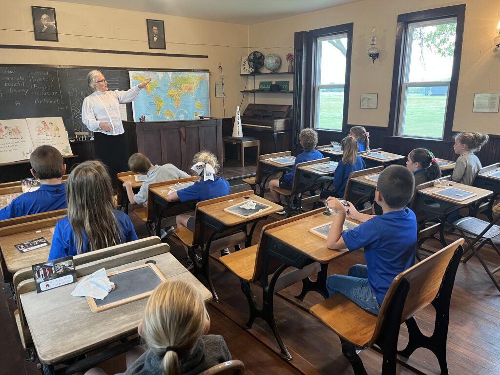 An early 1900's schoolmarm teaching children in a one-room schoolhouse.