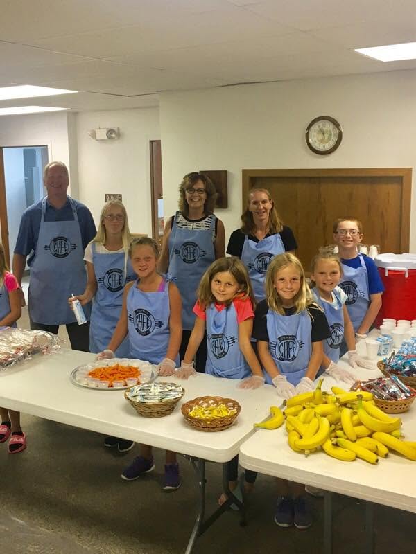 Adults and kids volunteering to serve a meal.