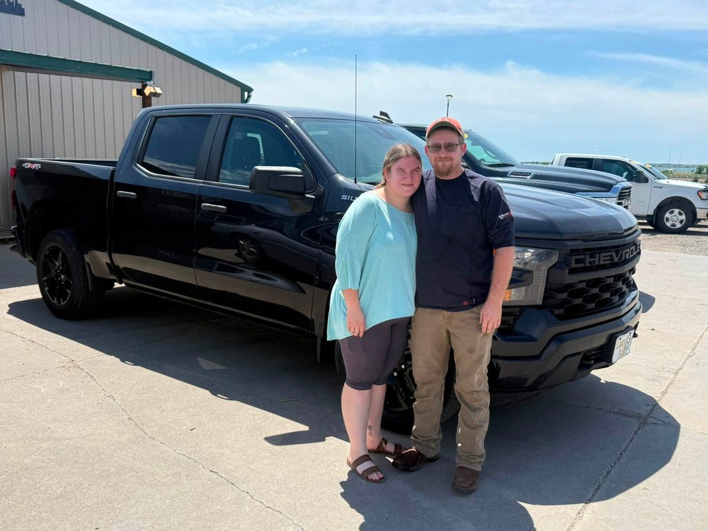 A couple stands in front of their newly purchased truck.